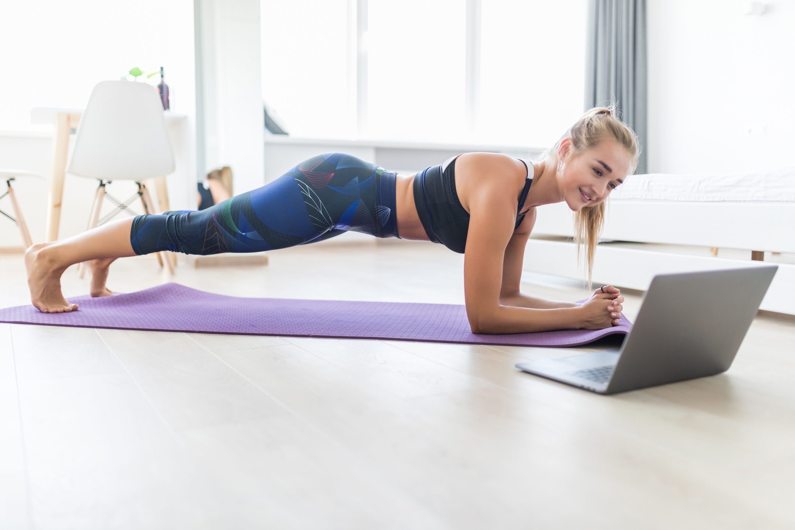 Attractive sportswoman with laptop doing push ups at home. Formation d’instructeurs Yoga